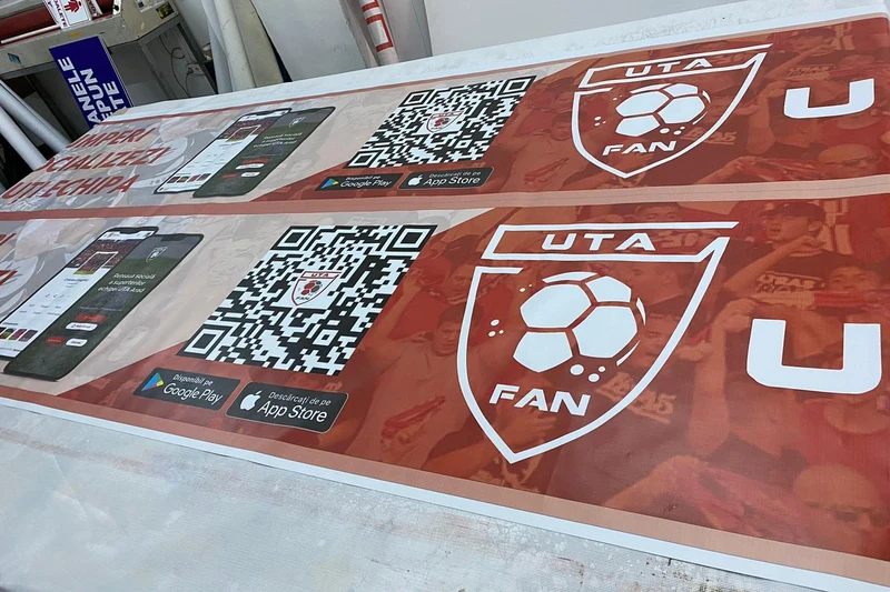 Doua bannere publicitare 6×1 m fan club local imprimate complet, vedere oblica pe masa de productie in atelierul Mora Group — print large format cu cerneluri rezistente UV