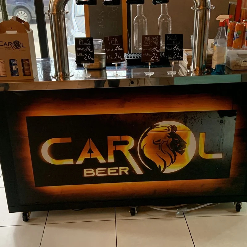 Colantare front bar bere artizanala cu logo iluminat backlit — "Bere Artizanala" cu silueta de leu in finisaj gold, instalat in interior pub cu robinete de bere artizanala si tablite ardezie cu preturi PILS, IPA, BRUNA, ROSCATA