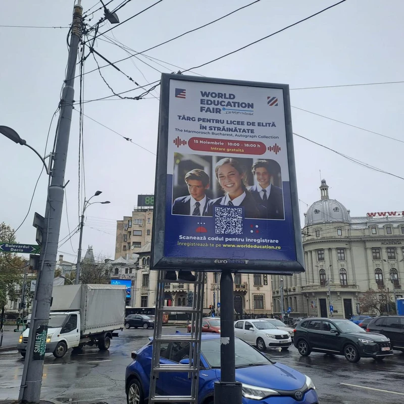 Citylight Mora Group cu campanie World Education Fair targ pentru licee de elita in strainatate, montat in Piata Romana cu cladirea Academia de Studii Economice (cupola si fatada www.ase.ro) in fundal si indicator Bulevardul Dacia