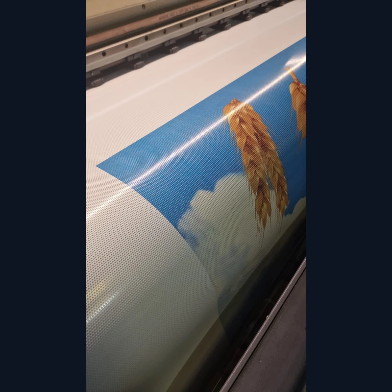 Detaliu textura PVC perforat one-way vision printat pentru window graphics Cereale si furaje la Ilie — material translucid cu micro-perforatii uniforme si grafica spice de grau pe fundal cer, productie large-format in atelierul Mora Group